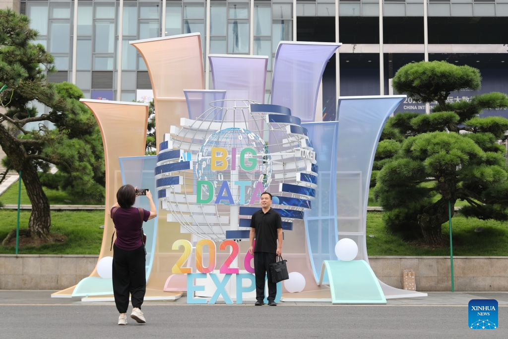 A visitor poses for a photo in front of a logo of the 2026 China International Big Data Industry Expo in Guiyang, southwest China's Guizhou Province, Aug. 28, 2026. The 2026 China International Big Data Industry Expo opened on Friday.  Themed "Token: A New Path to Value of Data Elements," the expo has attracted 372 domestic and international companies and over 16,000 registered guests. (Xinhua/Li Xulun)