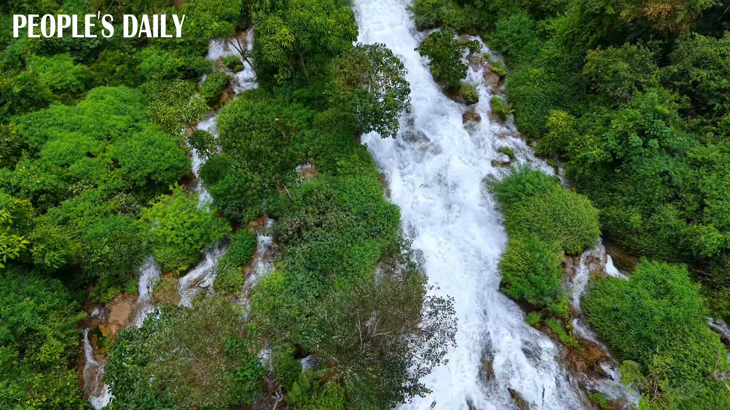 Waterfall flows down lush mountainside in SW China's Guizhou