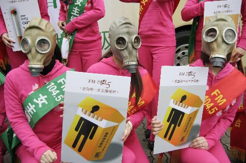 Mask-wearing radio hostesses hold anti-smoking posters in Hangzhou