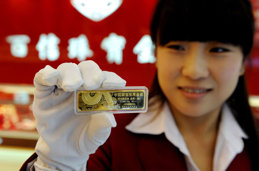 A staff worker shows off the gold bar for the Chinese year of the Snake in a Tianjin jewellery store on Nov. 4. This so-called Chinese zodiac gold bar debuts in the city and comes in five weight categories: 50g, 100g, 200g, 500g and 1,000g. (Xinhua)