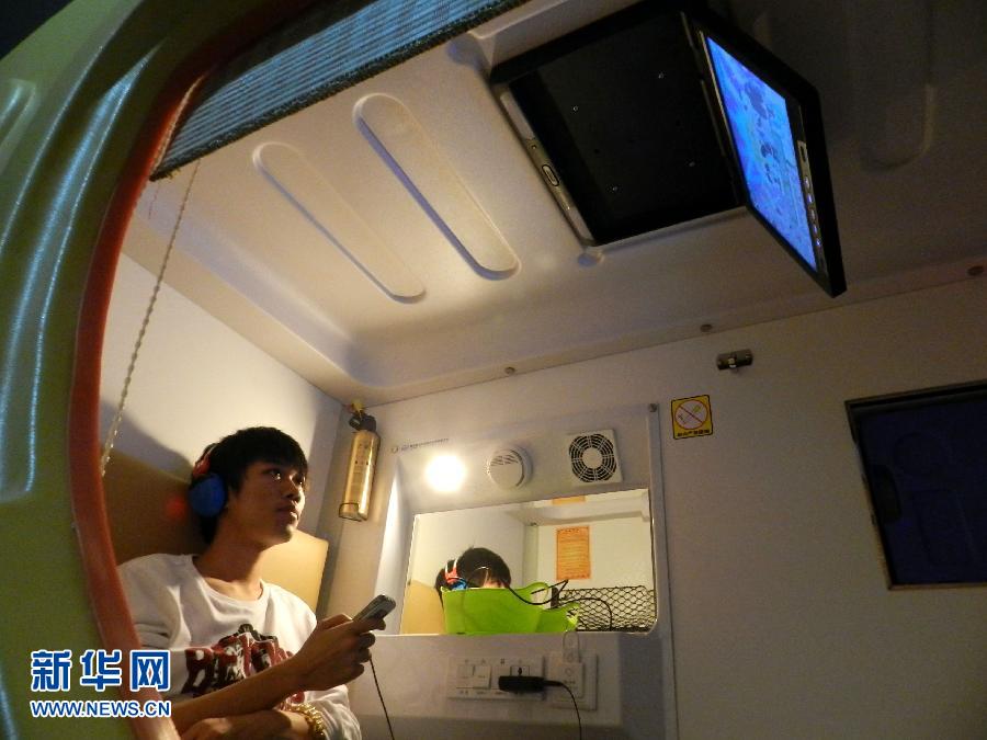 A young tourist watches digital television in a capsule hotel. (Photo/ Xinhua) 