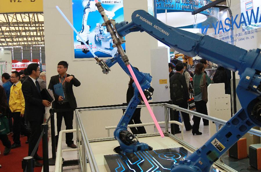 Visitors watch two industrial robots performing martial arts at the 2012 China International Industry Fair in east China's Shanghai Municipality, Nov. 6, 2012. The five-day Fair, which kicked off on Tuesday, is held in November annually since 1999. (Xinhua/Pei Xin)