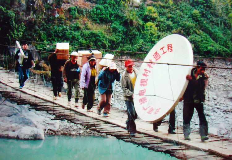 Photo shows technical staff carrying the satellite television receiving equipment to the mountain villages in Yunnan province. (People's Daily Online/ Jiang Jianhua)