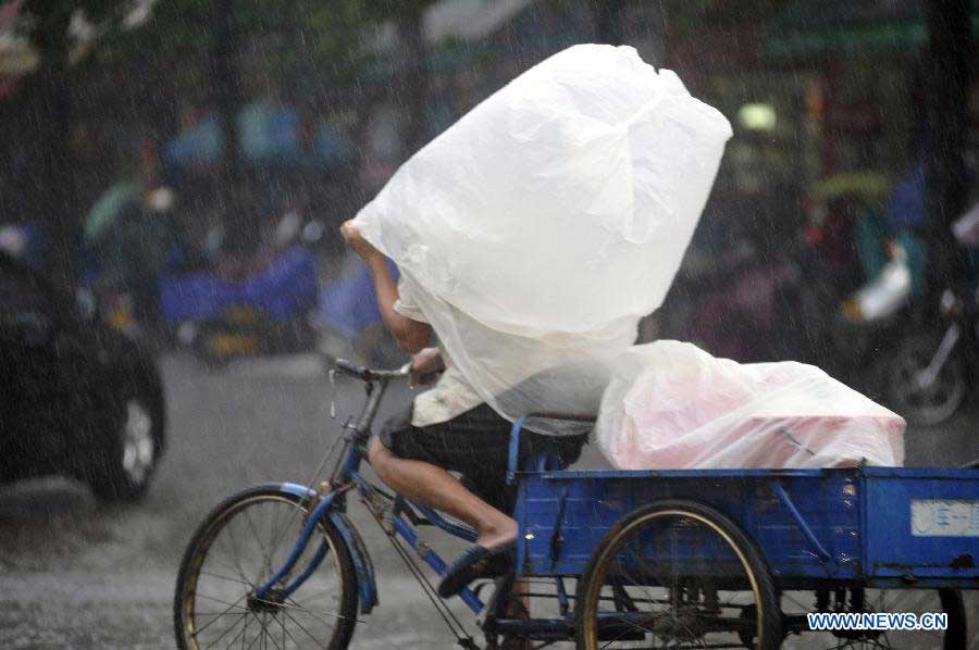 A citizen rides against the heavy rain with a plastic bag covering his head in a street of Qionghai City, south China's Hainan Province, Nov. 6, 2012. Rainy weather appeared in some places of Qionghai City on Tuesday. (Xinhua/Meng Zhongde) 