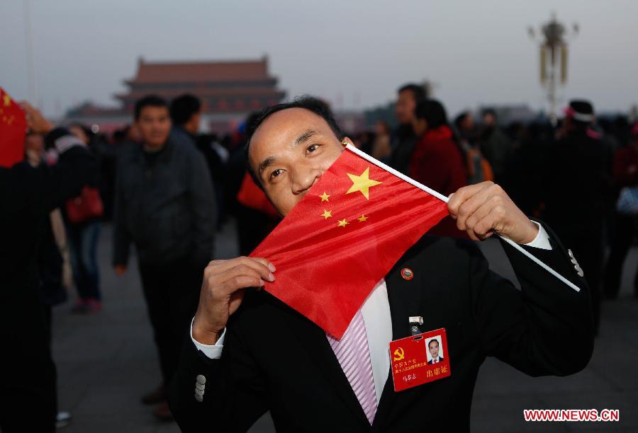 Ma Gongzhi, a delegate of the 18th National Congress of the Communist Party of China (CPC) from central China's Hunan Province, kisses the national flag at the Tian'anmen Square in Beijing, capital of China, Nov. 7, 2012. Tourists from across the country and local residents watched the national flag-raising ceremony at the square early Nov. 7, one day ahead of the opening of the 18th CPC National Congress. (Xinhua/Jin Liwang)