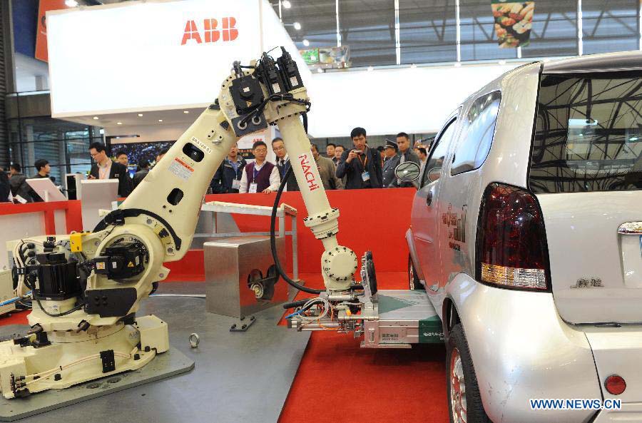 An industrial robot changes batteries for a new energy vehicle at the 2012 China International Industry Fair in east China's Shanghai Municipality, Nov. 6, 2012. The industry fair, with the participation of 63 colleges displaying a lot of scientific projects including 51 major technological achievement projects, was open to the public on Tuesday. (Xinhua/Lai Xinlin)
