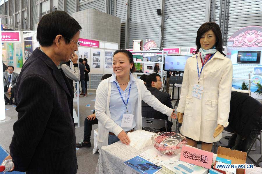 A robot interacts with visitors under the guidance of staff members at the 2012 China International Industry Fair in east China's Shanghai Municipality, Nov. 6, 2012. The industry fair, with the participation of 63 colleges displaying a lot of scientific projects including 51 major technological achievement projects, was open to the public on Tuesday. (Xinhua/Lai Xinlin)
