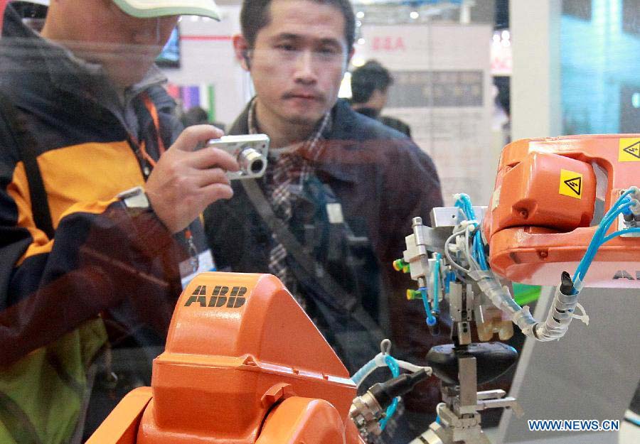 Visitors watch an industrial robot assembling a mouse at the 2012 China International Industry Fair in east China's Shanghai Municipality, Nov. 6, 2012. The five-day Fair, which kicked off on Tuesday, is held in November annually since 1999. (Xinhua/Pei Xin) 