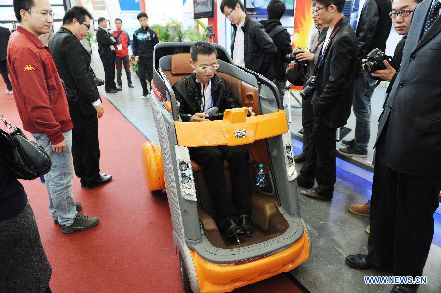 A visitor takes a test-drive of a new energy vehicle at the 2012 China International Industry Fair in east China's Shanghai Municipality, Nov. 6, 2012. The industry fair, with the participation of 63 colleges displaying scientific projects including 51 major technological achievement projects, was open to the public on Tuesday. (Xinhua/Lai Xinlin)