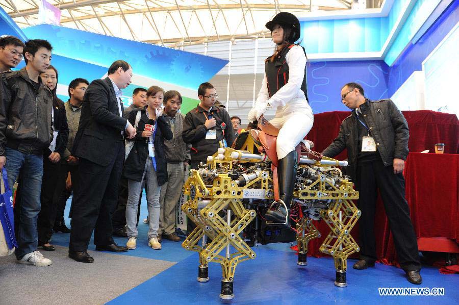 Visitors watch a robot at the 2012 China International Industry Fair in east China's Shanghai Municipality, Nov. 6, 2012. The industry fair, with the participation of 63 colleges displaying a lot of scientific projects including 51 major technological achievement projects, was open to the public on Tuesday. (Xinhua/Lai Xinlin)