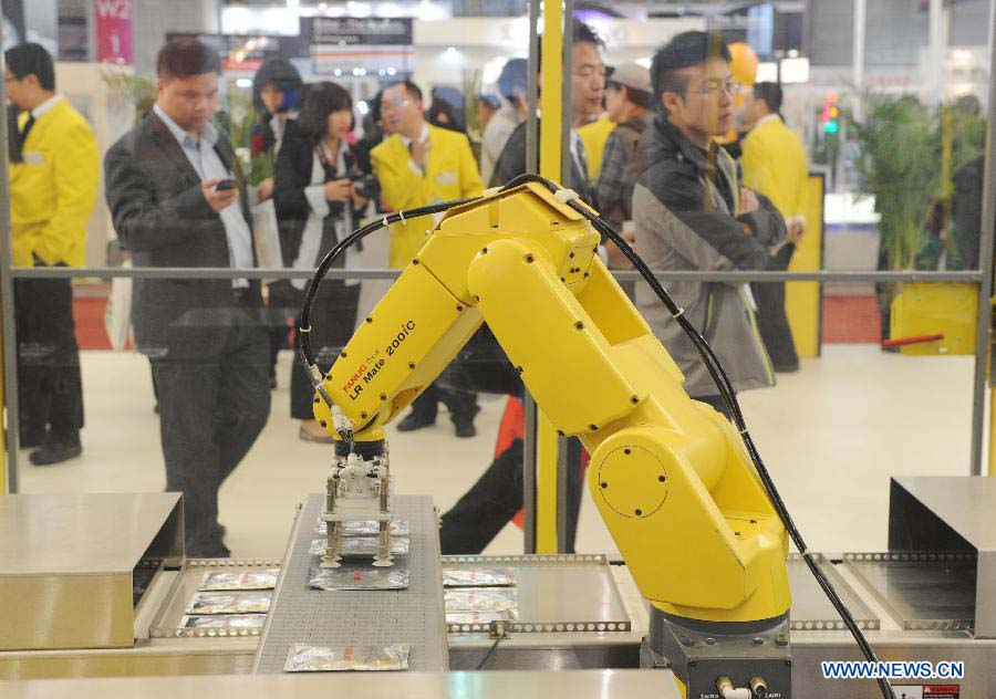 Visitors watch a robot operating on the production line at the 2012 China International Industry Fair in east China's Shanghai Municipality, Nov. 6, 2012. The industry fair, with the participation of 63 colleges displaying a lot of scientific projects including 51 major technological achievement projects, was open to the public on Tuesday. (Xinhua/Lai Xinlin)