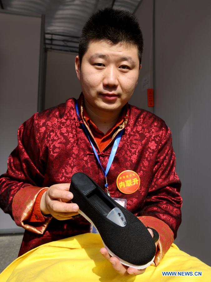 Ren Chenyang, a Beijing-based shoemaker, presents a cloth shoe at the China Huangshan Intangible Cultural Heritage Skills Exposition in Huangshan, east China's Anhui Province, Nov. 7, 2012. A total of 237 Chinese intangible cultural heritage items will be exhibited during the five-day event, which opened here on Wednesday. (Xinhua/Xu Zijian)