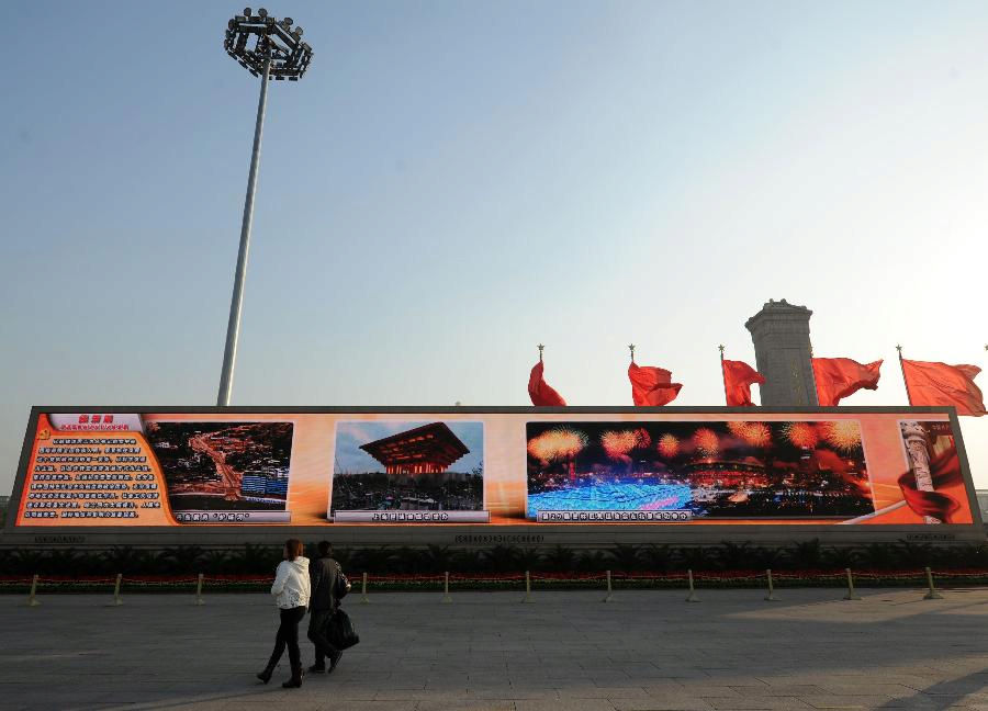 Visitors watch a large screen displaying achievements which China has gained under the leadership of the Communist Party of China (CPC) in the past decade, at the Tian'anmen Square in central Beijing, capital of China, Nov. 8, 2012. The 18th CPC National Congress was opened in Beijing on Thursday. (Xinhua/Luo Xiaoguang)