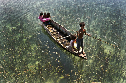 Semporna, Malaysia.Children propel a canoe in the river, which looks like patrolling in the sky. 
