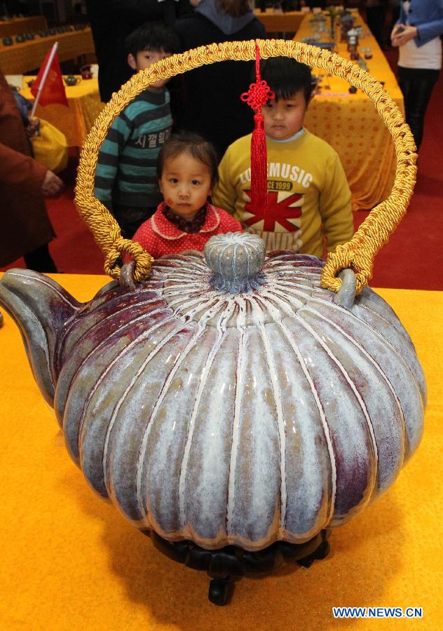 Two kids look at a pot displayed at Henan Jun porcelain pots design competition in Yuzhou City of Xuchang, central China's Henan Province, Nov. 10, 2012. Jun porcelain, one of the five top porcelains in China, is famous for the amazing change of its color during the process of firing in kilns. (Xinhua/Niu Shupei)