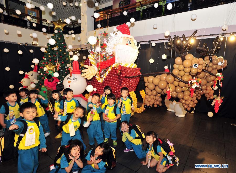 Children pose for group photos in front of Santa Claus and reindeer made up of balloons during the "BOOMBOOM" Balloon Doll Exhibition at the Puppetry Art Center of Taipei, southeast China's Taiwan, Nov. 9, 2012. (Xinhua/Wu Ching-teng) 