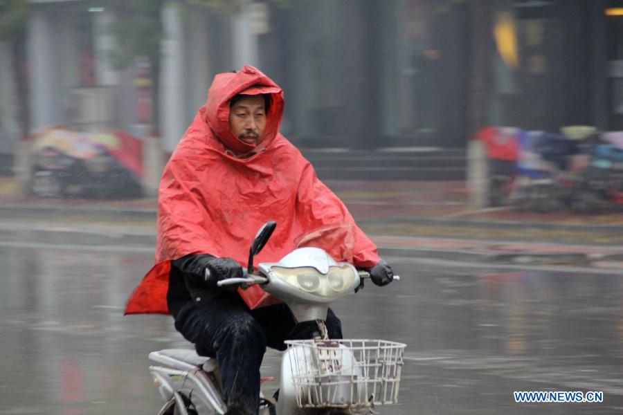 A local resident rides an electric bicycle in the rain in Neihuang County of Anyang City, central China's Henan Province, Nov. 10, 2012. A strong cold snap has brought rainfall and wind to many parts of northern China since Friday night, causing a fall in temperature and scattered snowfall in the following days. (Xinhua/Liu Xiaokun)