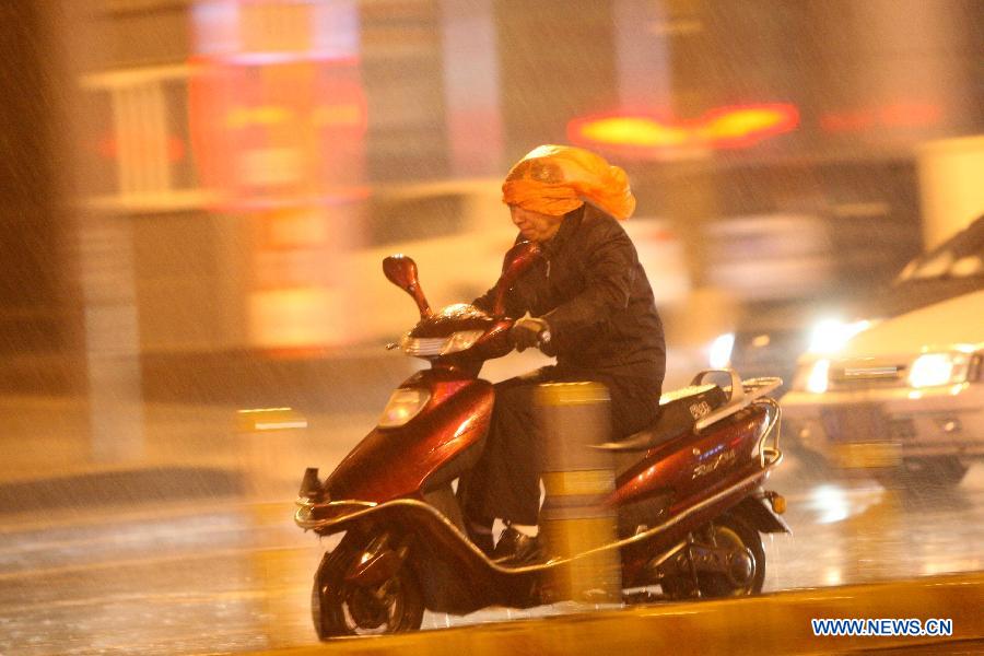 A citizne rides a motorcycle in the rain on Beima Road of Yantai City, east China's Shandong Province, Nov. 10, 2012. A strong cold snap brought rainfall and wind to the coastal city, causing a fall in temperature. (Xinhua/Shen Jizhong)