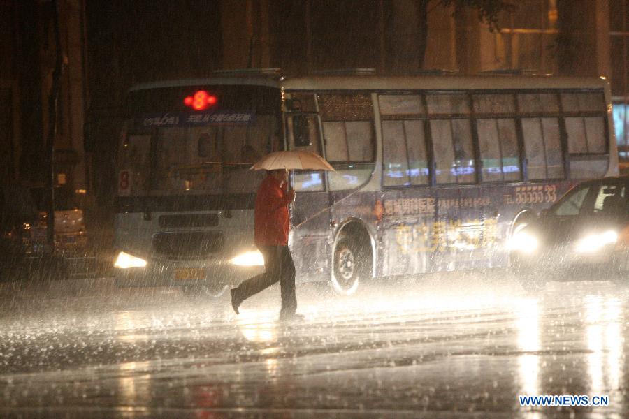 A citizen walks in the rain on Beima Road of Yantai City, east China's Shandong Province, Nov. 10, 2012. A strong cold snap brought rainfall and wind to the coastal city, causing a fall in temperature. (Xinhua/Shen Jizhong)