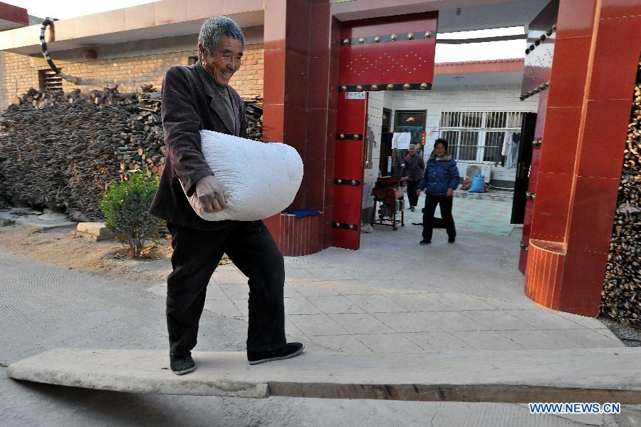 A man carries a bag of corn at Yaotou Village of Pinglu County, north China's Shanxi Province, Nov. 6, 2012. The grain production of Shanxi Province this year is expected to exceed 12 billion kilograms, hitting a record high. (Xinhua/Zhan Yan) 