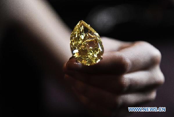 A model presents the Sun-Drop Diamond to meida at a hotel in Geneva, Switzerland, Nov. 9, 2011. The Sun-Drop is a sensational fancy vivid yellow pear-shaped diamond weighing 110.03 carats and is known as the largest pear-shaped fancy vivid yellow diamond in the world. (Xinhua/Yu Yang)