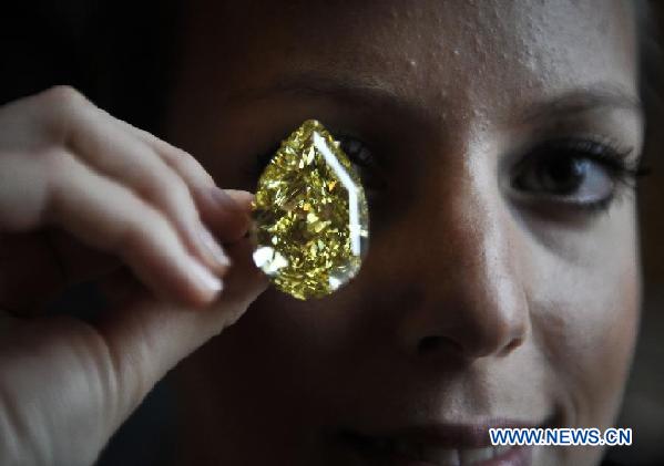 A model presents the Sun-Drop Diamond to meida at a hotel in Geneva, Switzerland, Nov. 9, 2011. The Sun-Drop is a sensational fancy vivid yellow pear-shaped diamond weighing 110.03 carats and is known as the largest pear-shaped fancy vivid yellow diamond in the world. (Xinhua/Yu Yang)