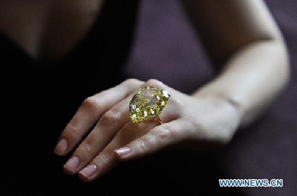 A model presents the Sun-Drop Diamond to meida at a hotel in Geneva, Switzerland, Nov. 9, 2011. The Sun-Drop is a sensational fancy vivid yellow pear-shaped diamond weighing 110.03 carats and is known as the largest pear-shaped fancy vivid yellow diamond in the world. (Xinhua/Yu Yang)