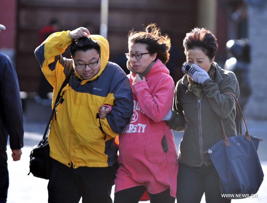 Tourists walk in strong wind at the Tiantan Park in Beijing, capital of China, Nov. 11, 2012. Beijing experienced windy weather and a sharp fall in temperature on Sunday following a rainfall the previous day. (Xinhua/Li Wen) 