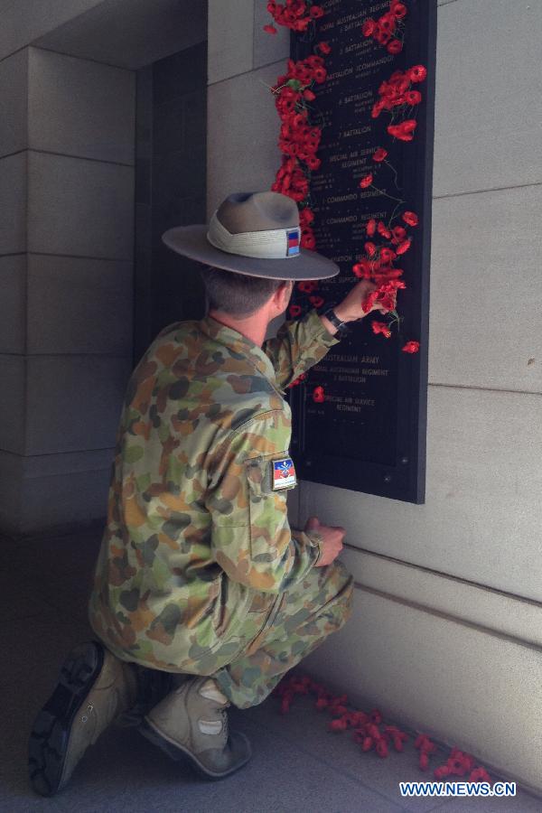 A man puts poppy flowers on the wall showing the names of martyrs in the War Memorial in Canberra, Australia, Nov. 11, 2012. Ceremonies marking the 11th hour of the 11th day of the 11th month, remember the moment in 1918 when the guns of the World War I fell silent. (Xinhua/Justin Qian)