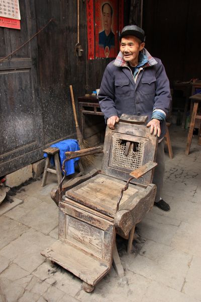 An old man in Chengkan shows off a German chair imported over a century ago. (CRIENGLISH.com/William Wang)