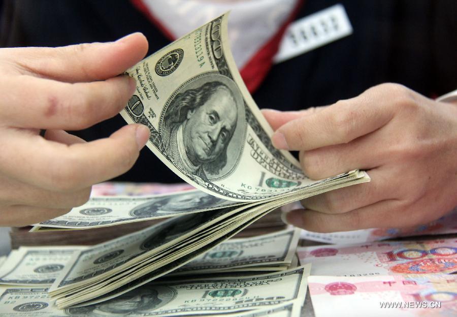 A worker counts the U.S. dollars at a bank in Tancheng County of Linyi City, east China's Shandong Province, Nov. 12, 2012. The Renminbi strengthened 92 basis points to 6.2920 against the U.S. dollar on Monday, according to the China Foreign Exchange Trading System. (Xinhua/Zhang Chunlei) 