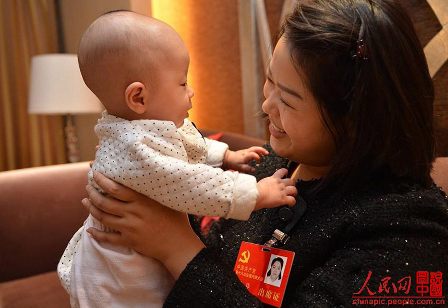 Luo Wei, a deputy to the 18th National Congress of the Communist Party of China, takes care of her five-month-old daughter in a hotel after a group discussion in Beijing on Nov. 10, 2012. Luo, who took her baby to Beijing as she is still breastfeeding, is the youngest deputy of Sichuan province delegation. She donated 55 percent of her liver to save the life of an unrelated person in 2005. (Photo/ People’s Daily Online)