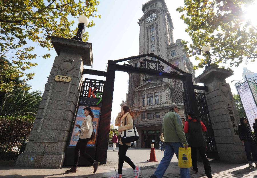 Pedestrians walk past the gate of the former site of Shanghai Art Museum in east China's Shanghai Municipality, Nov. 11, 2012.