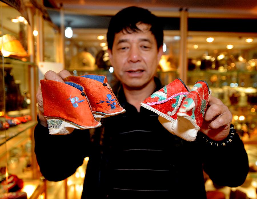 Tong Fucun shows two pieces of his collection in Taiyuan, capital of north China's Shanxi Province, Nov.11, 2012. (Xinhua/Yan Yan) 