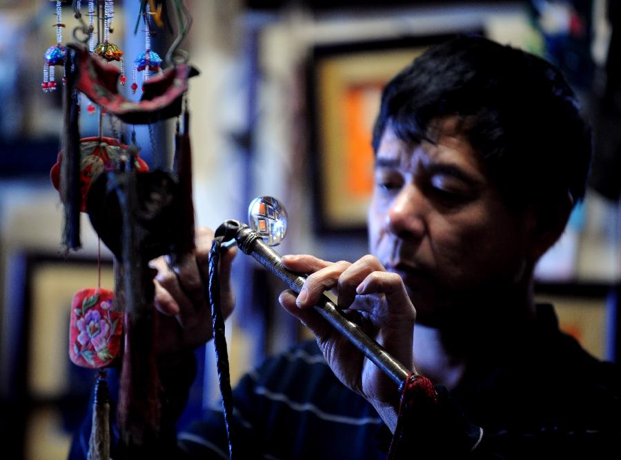 Tong Fucun looks at a piece of his collection in Taiyuan, capital of north China's Shanxi Province, Nov.11, 2012. Aged 46, Tong Fucun is an amateur collector. Decades of collecting formed a decent collection in Tong's apartment and basement, where over 10 thousand pieces of handicrafts are displayed. (Xinhua/Yan Yan) 