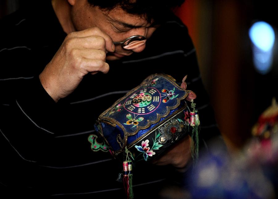 Tong Fucun looks at a piece of his collection in Taiyuan, capital of north China's Shanxi Province, Nov.11, 2012. (Xinhua/Yan Yan) 