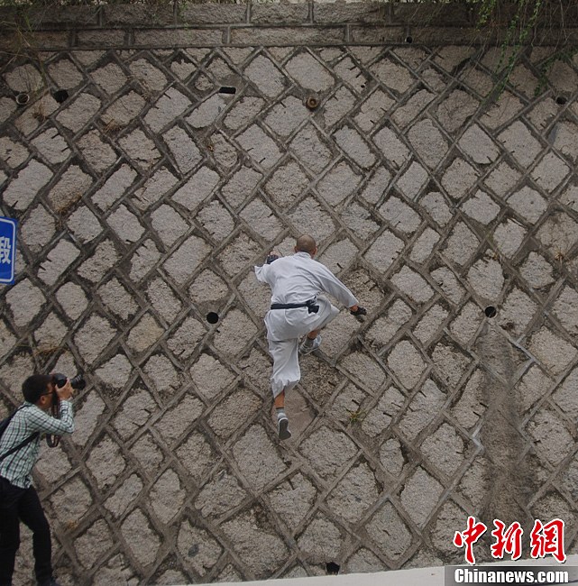 Shi Liliang, a monk from Southern Shaolin Temple, performs a Chinese martial art stunt by walking on a wall in Quanzhou, Fujian province, Nov 12, 2012. (CNSPHOTO/Su Qiaofeng)