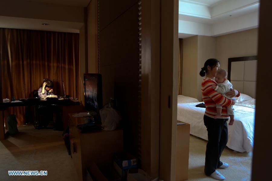 Jiang Min, a delegate to the 18th National Congress of the Communist Party of China (CPC), takes a call at her hotel room while a nanny helps her to take care of the baby in Beijing, capital of China, Nov. 13, 2012.(Xinhua/Jin Liwang)