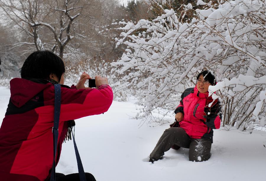 A citizen poses for photos in the snowy scenery in Changchun, capital of northeast China's Jilin Province, Nov. 13, 2012. The city witnessed a heavy snow since Monday. (Xinhua/Xu Chang) 