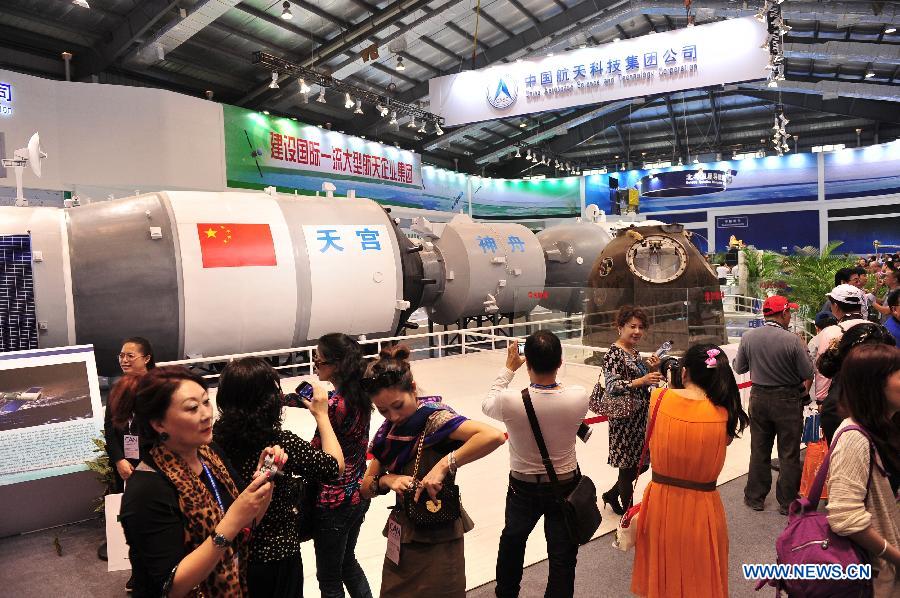 Visitors look at a model simulated the combination of the Tiangong-1 and Shenzhou spacecraft displayed by the China Aerospace Science and Technology Corporation, during the 9th China International Aviation and Aerospace Exhibition in Zhuhai, south China's Guangdong Province, Nov. 13, 2012. Some 650 manufactures at home and abroad attended the six-day airshow kicked off on Tuesday, which was expected to receive 400,000 visitors. (Xinhua/Yang Guang)
