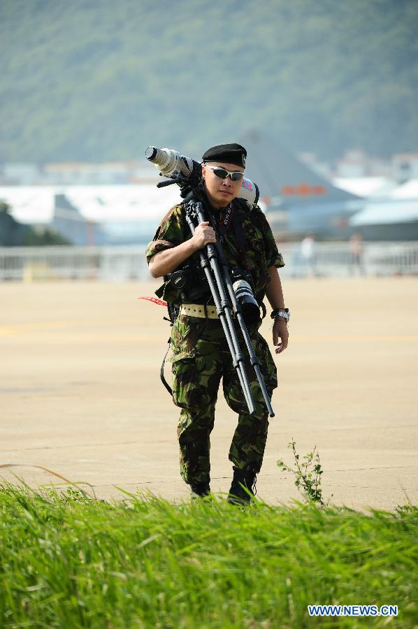 A photographer carries recording equipments in the 9th China International Aviation and Aerospace Exhibition in Zhuhai, south China's Guangdong Province, Nov. 11, 2012. The exhibition has attracted a large number of photograghers. Some of them are from media, some are from aviation industry corporations and others are big fans of aviation. (Xinhua/Yang Guang)