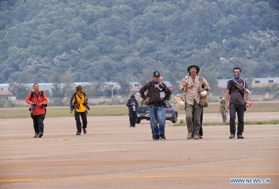 Photographers walk to the spot for recording flight displays during the 9th China International Aviation and Aerospace Exhibition in Zhuhai, south China's Guangdong Province, Nov. 11, 2012. The exhibition has attracted a large number of photograghers. Some of them are from media, some are from aviation industry corporations and others are big fans of aviation. (Xinhua/Yang Guang)