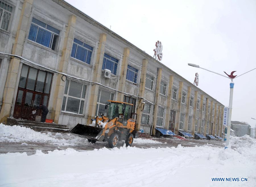 A forklift truck cleans snow piled in front of the Hegang Railway Station in Hegang, northeast China's Heilongjiang Province, Nov. 13, 2012. Heavy snowstorms swept northeastern regions of Heilongjiang since last Sunday, forcing highways to close. Local authority of railway service initiated an emergency plan to maintain order of stranded passengers. (Xinhua/Wang Kai) 