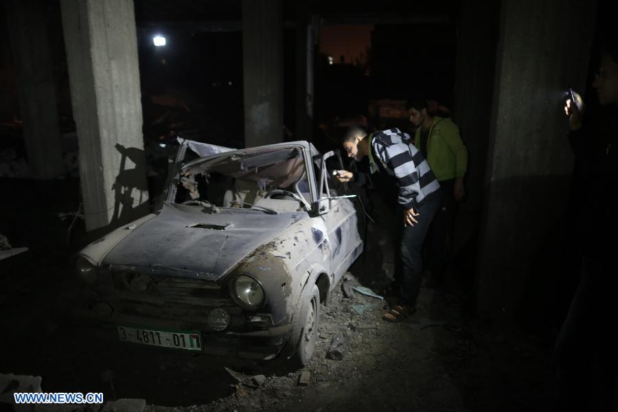 Palestinians check up a destroyed car following an Israeli air strike in Gaza City, on Nov. 14, 2012. Israel's air force, after killing Hamas' military leader in an air raid, on Wednesday continued striking Hamas targets, including its long-range rocket sites, in the Gaza Strip. (Xinhua/Wissam Nassar)