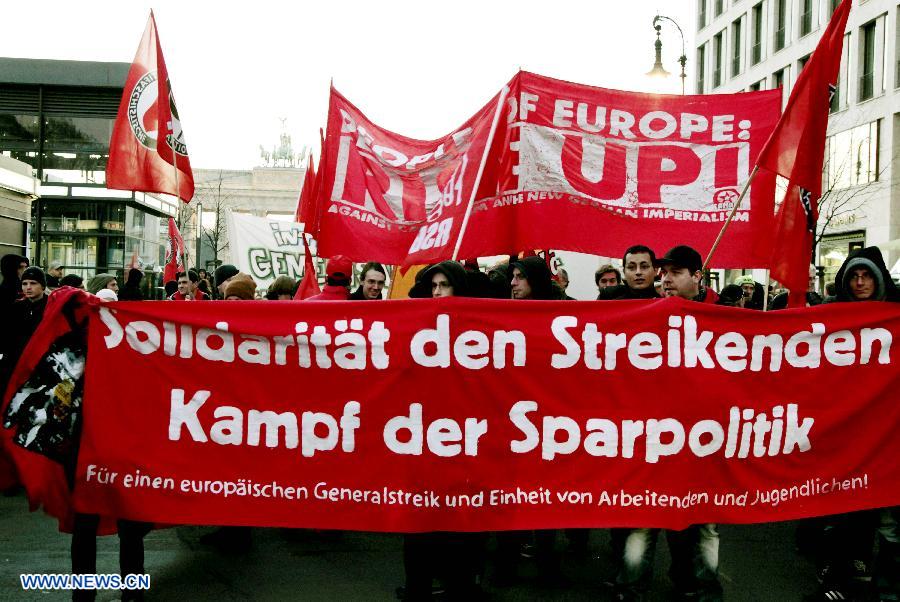 Protesters hold banners during an anti-austerity protest in front of the Brandenburg Gate in Berlin, Germany, Nov. 14, 2012. (Xinhua/Pan Xu)