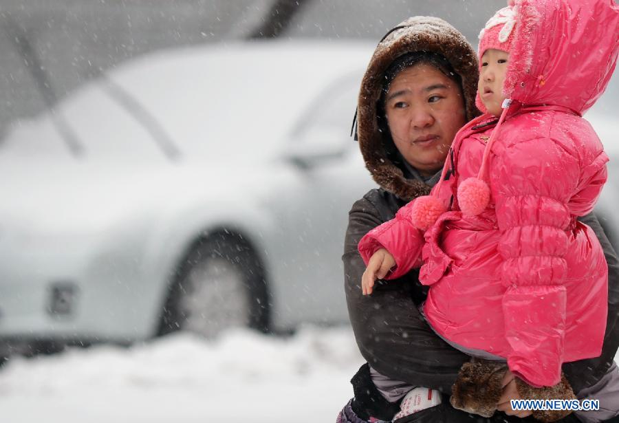 A citizen holding a child is seen in snow in Changchun, capital of northeast China's Jilin Province, Nov. 16, 2012. A snowfall hit central and eastern Jilin on Friday. (Xinhua/Lin Hong) 