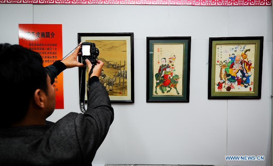 A visitor takes photo of artworks presented during an exhibition on the folk painting in Changchun, capital city of northeast China's Jilin Province, Nov. 16, 2012. (Xinhua/Xu Chang) 