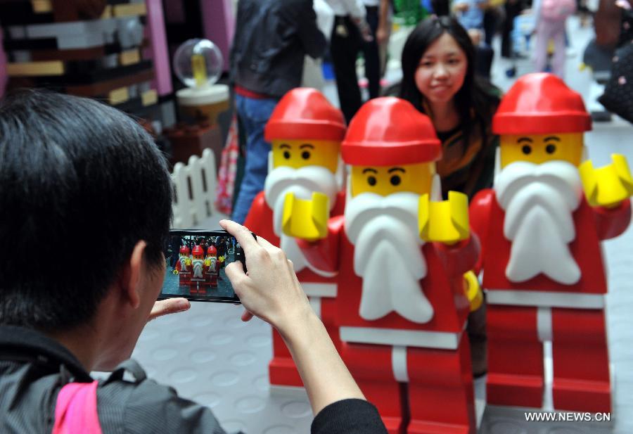 People take pictures with Santa Claus at the "Christmas village" built with building blocks at the Times Square in Causeway Bay in south China's Hong Kong, Nov. 16, 2012. As Christmas is drawing near, decorations have been used for creating atmosphere in Hong Kong. (Xinhua/Lo Ping Fai) 