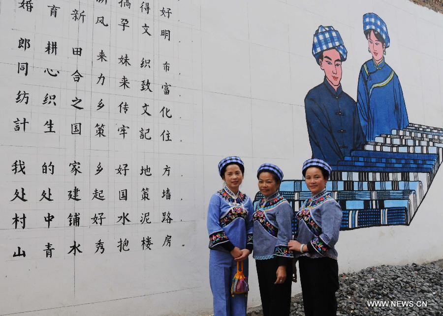 Women of Buyi ethnic group pose for photos in front of a picture depicting the hand-made cloth of their nationality at Wangmo County in Qianxinan Buyi and Miao Autonomous Prefecture, southwest China's Guizhou Province, Nov. 16, 2012. Weaving cloth plays an important role in the development of local economy. (Xinhua/Shi Xinrong)