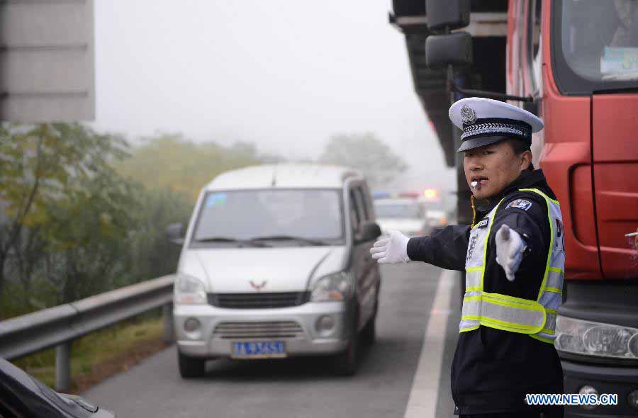 A traffic policeman directs traffic in the Changzhang section of the Shanghai-Kunming Highway in Nanchang, east China's Jiangxi Province, Nov. 19, 2012. The highways which closed because of dense fog in the province gradually reopened as the fog disappeared on Monday morning. (Xinhua/Zhou Mi) 